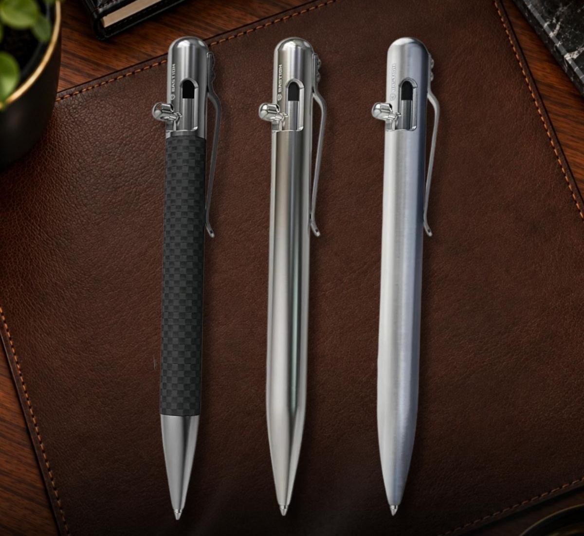 Three Bastion bolt action pens on a leather desk pad